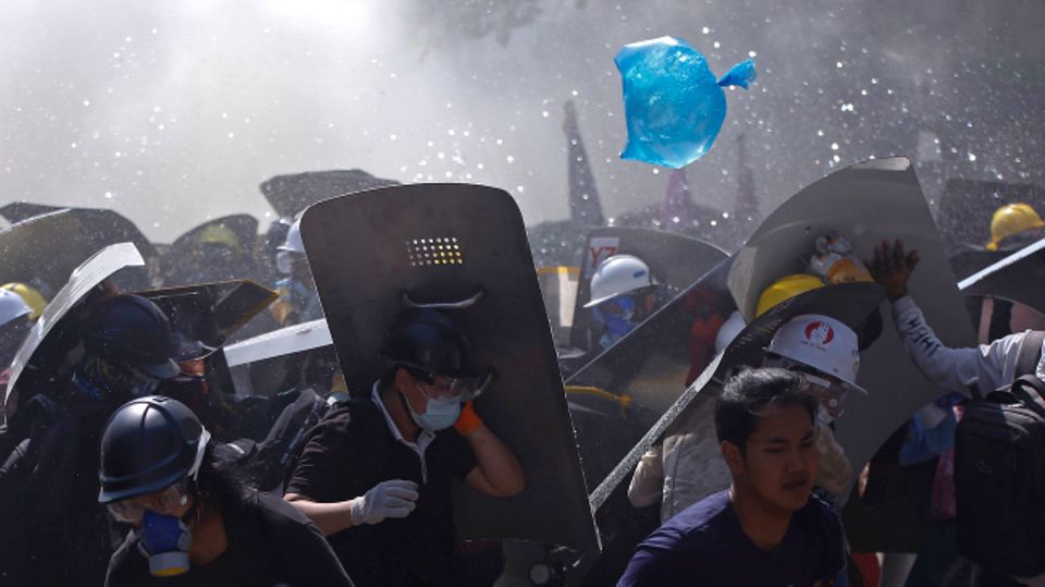 Menschen werden während eines Protests gegen den Putsch der Militärjunta auf einer Straße von der Polizei mit Tränengas auseinander getrieben