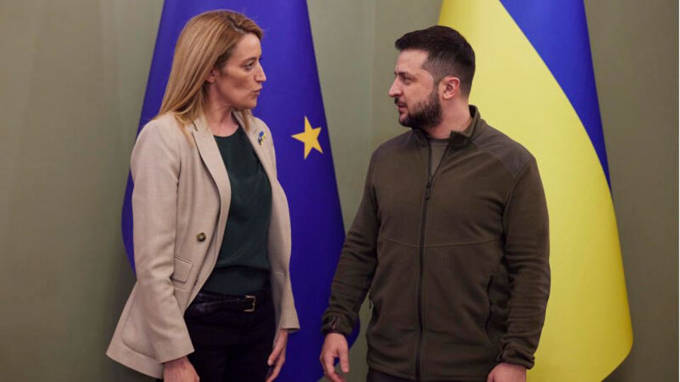 Roberta Metsola und Wolodymyr Selenskyj vor blau-gelben EU- und Ukraine-Fahnen