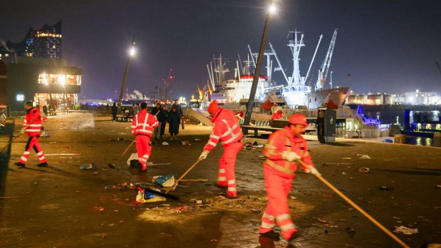 Mitarbeiter der Stadtreinigung Hamburg räumen abgebrannte Feuerwerkskörper und anderen Müll von der Promenade an den Landungsbrü
